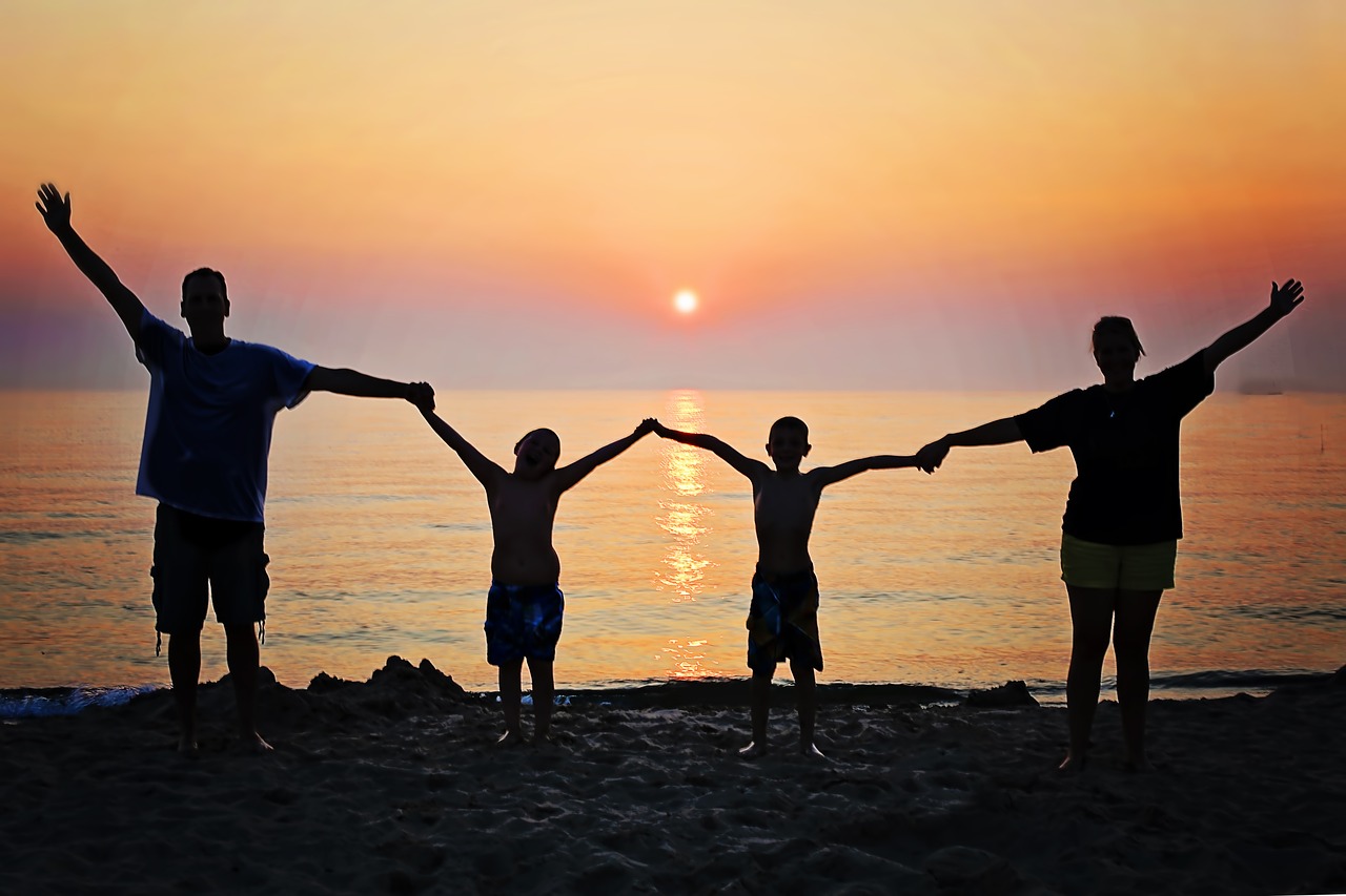 family holding hands on a beach at sunset