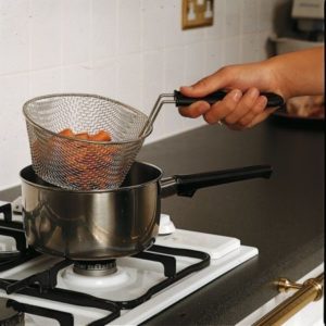 a cooking basket filled with vegetables being lifted out of a saucepan