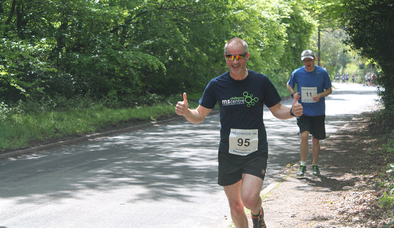 Runner with a Chiltrns MS Centre branded running vest giving a thumbs up as he takes part in Run Prestwood