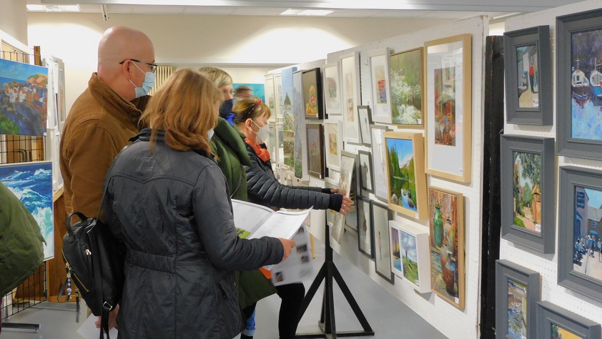 Group of people looking at painting hung up at a art exhibition.