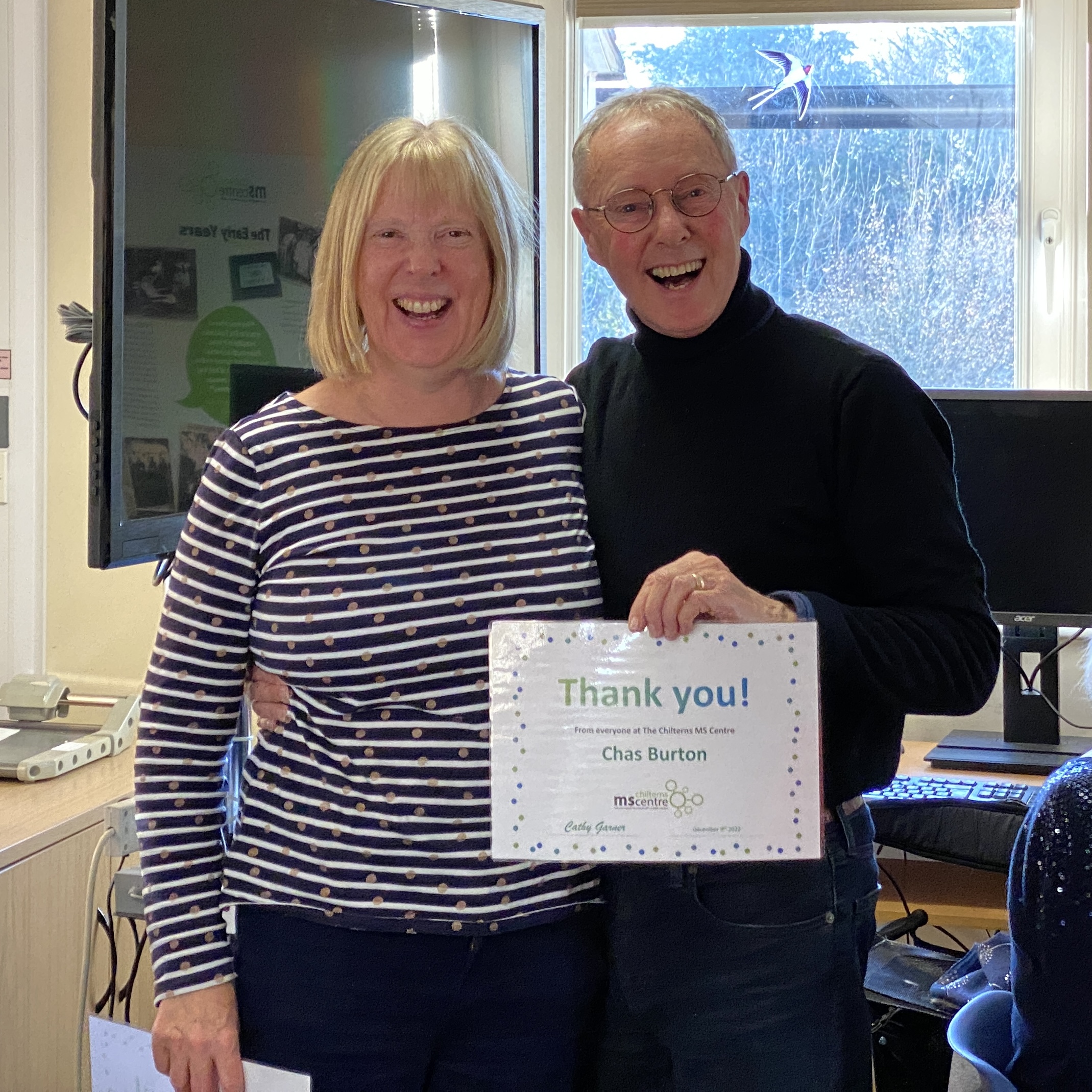 Smiling couple holding up a certificate saying thank you.