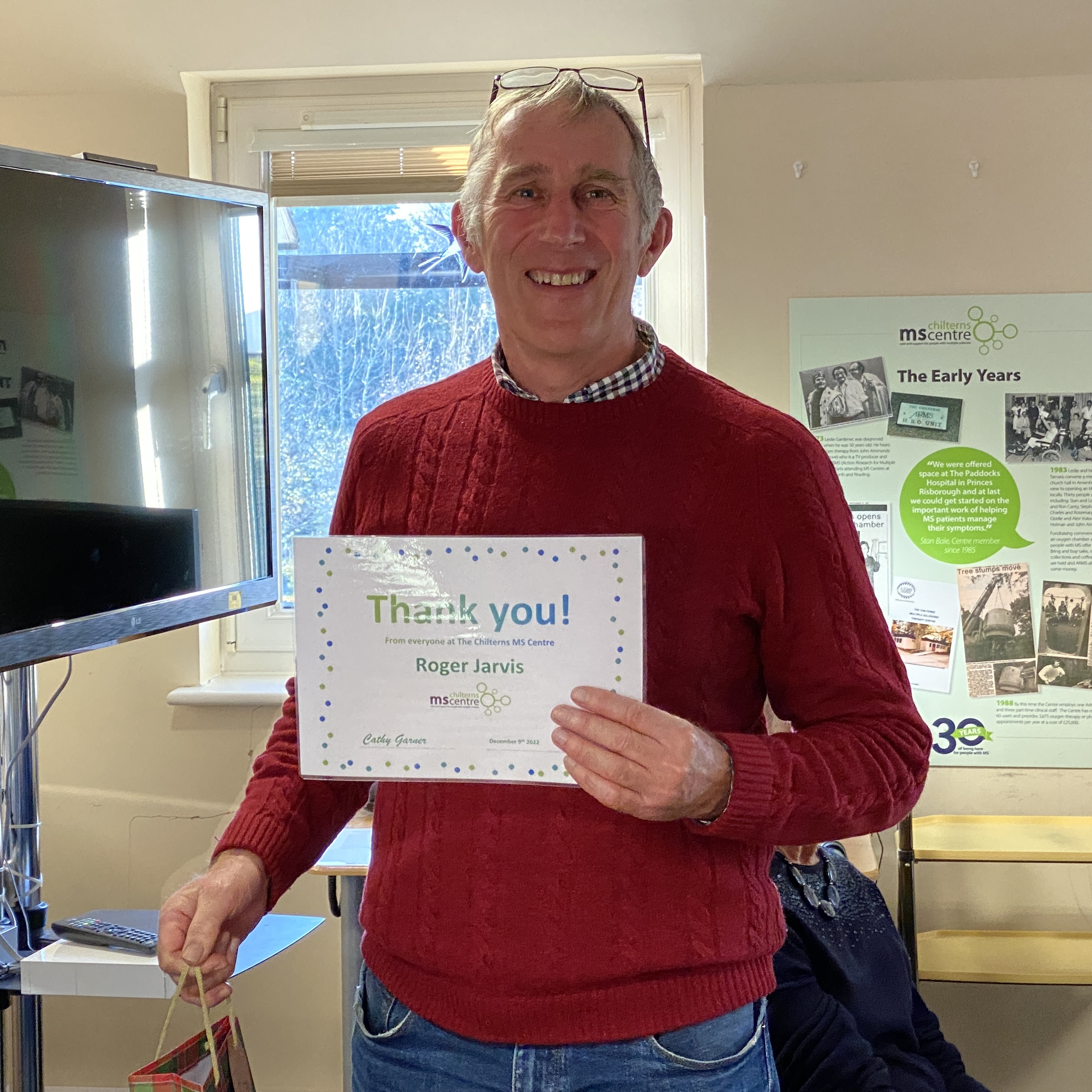 Smiling man holding up a certificate saying thank you.