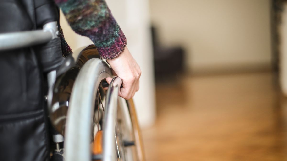 Close up of a man sitting in a wheelchair with his hand gripping the wheel bar.