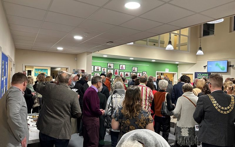 Crowd of people in an atrium listening to two people speaking at the front